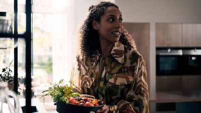 Eine junge Frau befindet sich in einer Küche und trägt Eine Obst und Gemüseschale。