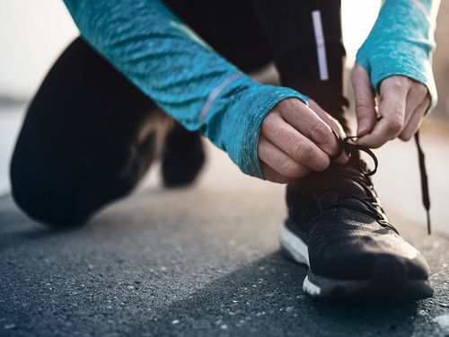 Adidas - Mann bindt sich Schuh in Sportsachen zu